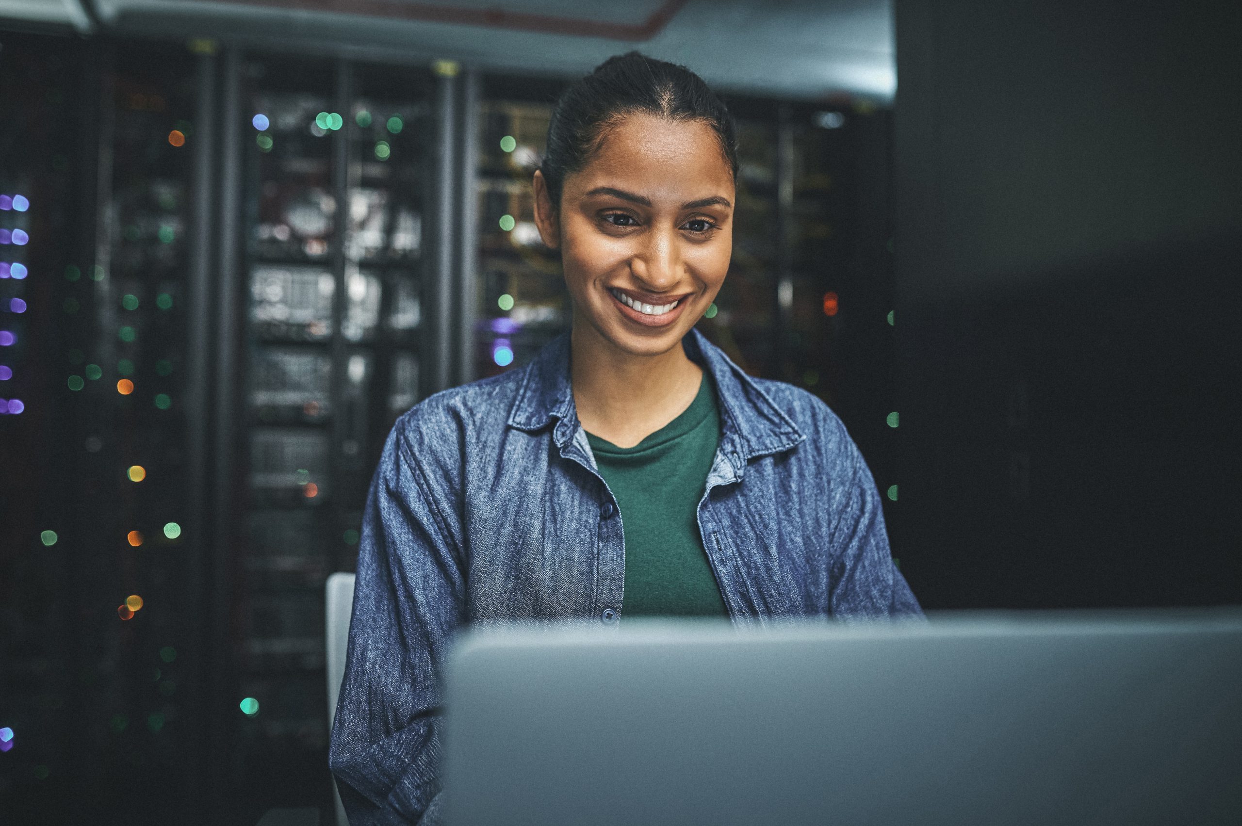 Shot of a female IT technician in a server room and using a laptop
