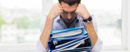 frustrated man with several binders in front of him